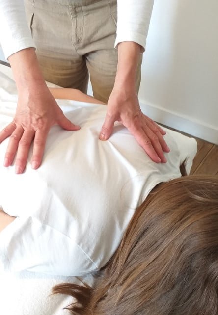 Une femme se fait masser dans une salle dédiée au shiatsu, entourée d'une ambiance sereine et relaxante