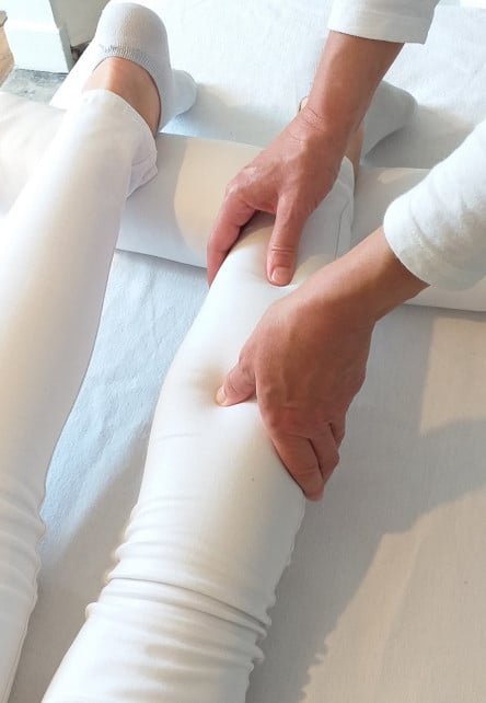 Une personne reçoit un massage de jambe par un praticien, mettant en avant la détente et le bien être